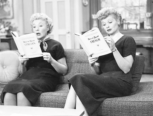 A scene from I Love Lucy. Lucy and Ethel sitting on a lounge reading
